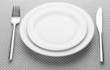 © Africa Studio - White empty plates with fork and knife on a grey tablecloth