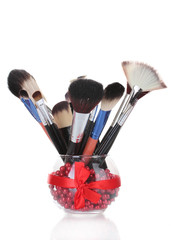 make-up brushes in glass vase isolated on white