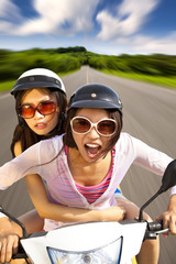 two girls riding scooter on the road