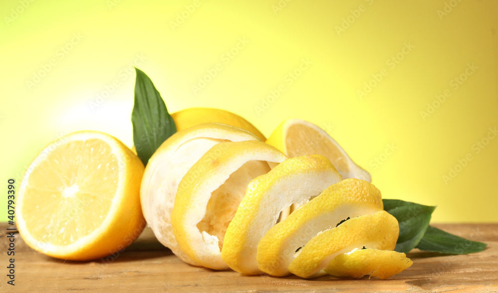 ripe lemons with leaves on wooden table on green background