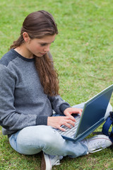 Poster - Serious young girl typing on her laptop while looking at the scr