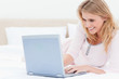 © WavebreakmediaMicro - Woman lying on the bed, using a laptop and smiling