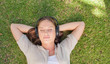 © WavebreakmediaMicro - Relaxed woman listening to music while lying on the lawn
