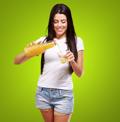 Wall Mural - portrait of young woman pouring orange juice on glass over green