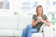 © WavebreakmediaMicro - Woman sitting in the corneer of the couch, smiling with cup in h