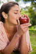 © WavebreakmediaMicro - Woman smells an apple while lying in grass
