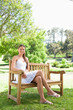 © WavebreakmediaMicro - Smiling woman with her legs crossed sitting on a bench
