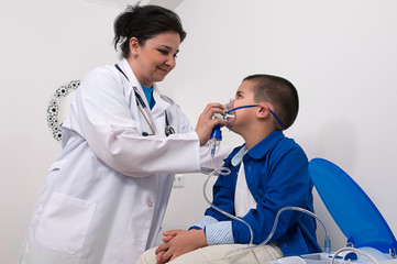 doctor applying oxygen treatment on a little boy with asthma.