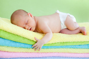 Fototapete - newborn baby girl weared cap sleeping on colourful towels