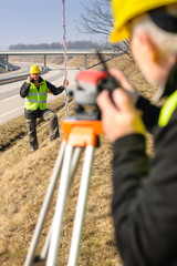 Geodesist measure land with tacheometer highway