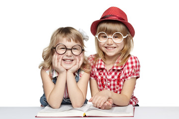 Two little girls in funny eyeglasses reading book