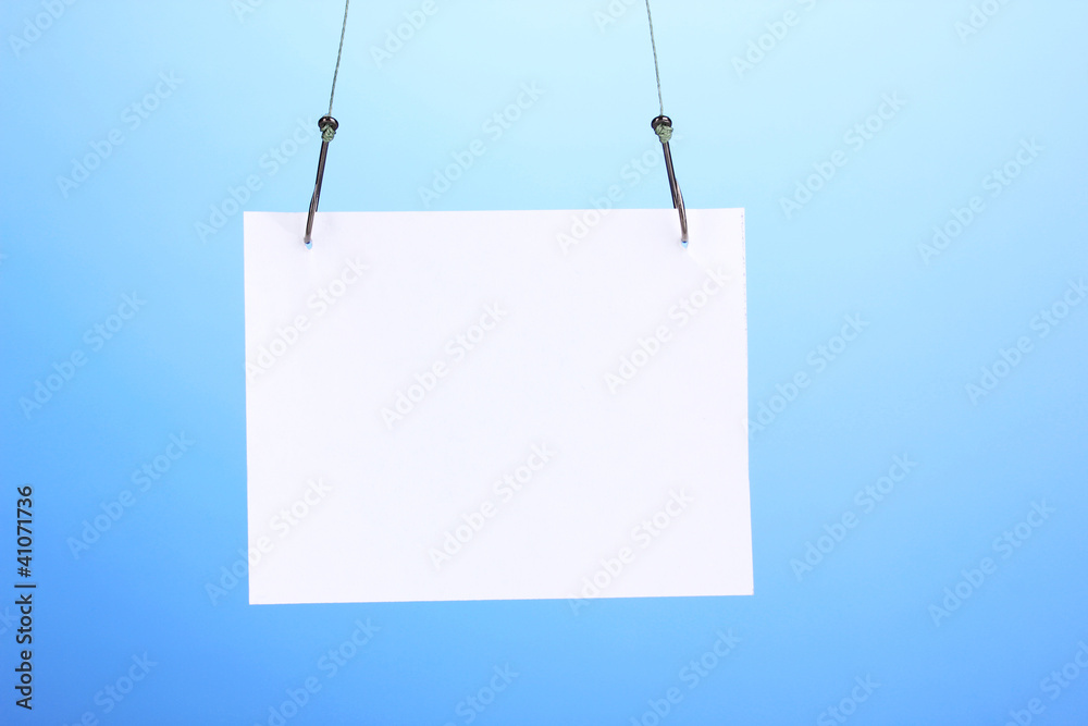 Empty sheet of a paper on fish hooks on blue background