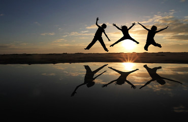 Canvas Print - silhouette of kids jumping on beach in sunset