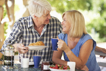 Senior couple eating breakfast outdoors