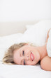 © WavebreakmediaMicro - Smiling woman lying under a white duvet