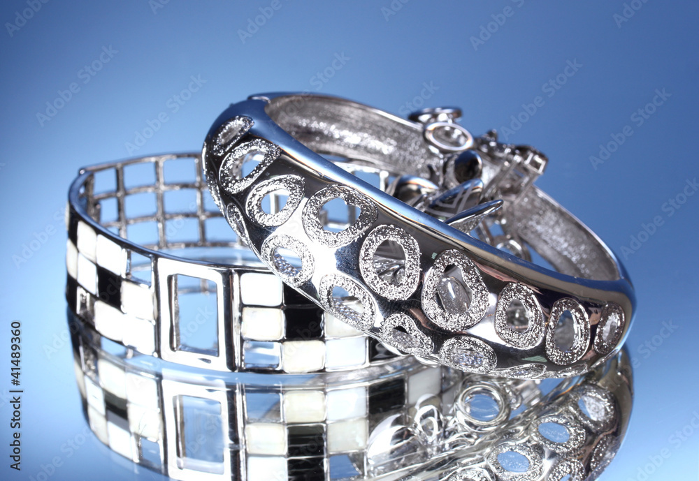 Beautiful silver bracelets on blue background