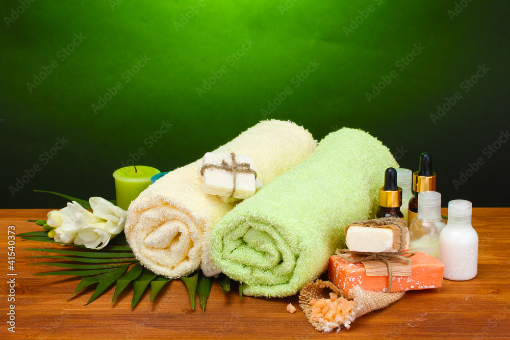 Spa setting on wooden table on green background