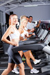 © michaeljung - group of fitness people running on treadmill in gym