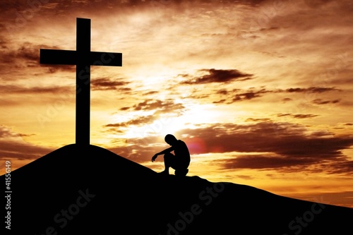 Fototapeta na wymiar Man sitting desperately under the cross