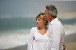 © auremar - Married couple dressed in white taking a walk along the beach