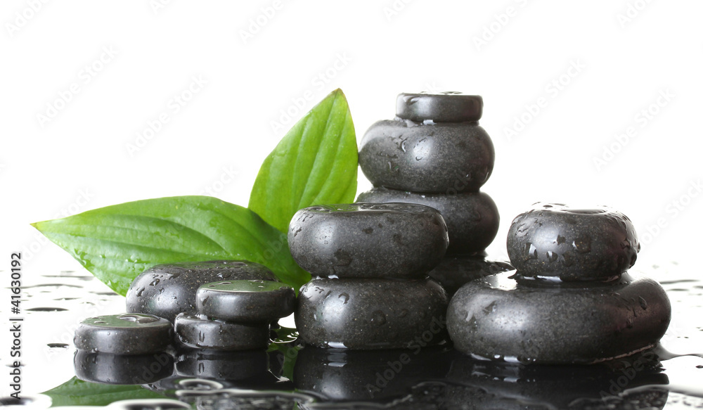 Spa stones with drops and green leaves on white background