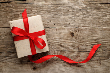 Gift box with red bow on wood background