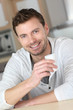 © goodluz - Portrait of handsome guy drinking coffee in home kitchen