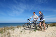 © goodluz - Couple standing on a sand dune with bicycles
