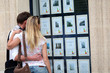 © goodluz - Couple looking at house-for-sale ads through shop window