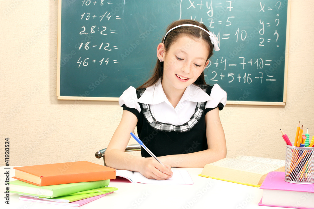 little schoolchild in classroom write in notebook