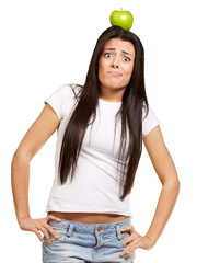 portrait of young woman holding green apple on her head over whi