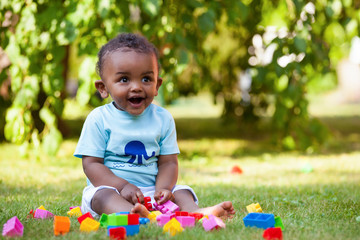 little african american baby boy playing in the grass