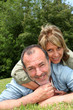 © goodluz - Senior couple having fun laying in grass