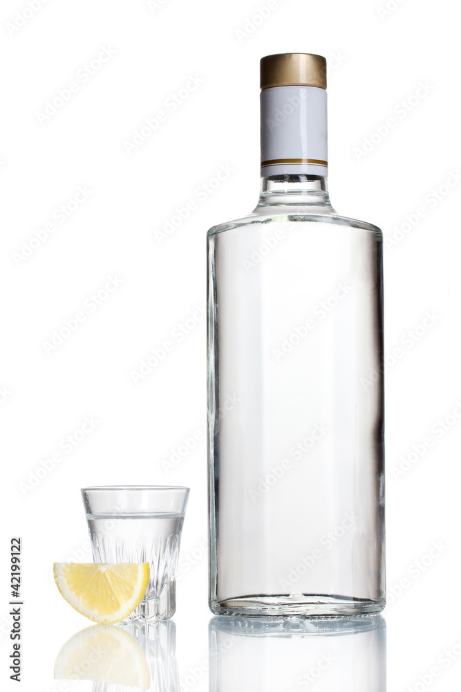 Bottle of vodka and wineglass with lemon isolated on white
