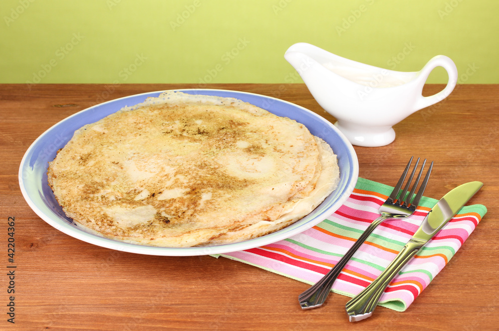 Stack of tasty pancakes on wooden table on green background