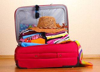 Open red suitcase with clothing in the room