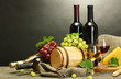 wine, cheese and grapes on wooden table on grey background