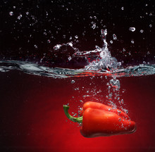 Red Pepper Falling Into Water. Background In The Same Tone