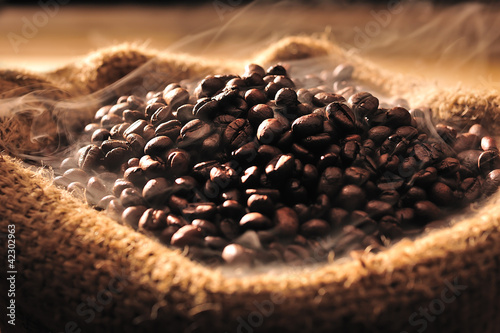 Fototapeta na wymiar Coffee beans with smoke in burlap sack
