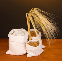 Poster - Flour and wheat grain on wooden table on dark background