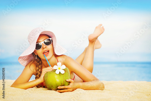 Nowoczesny obraz na płótnie Young woman in pink swimsuit with coconut cocktail on the beach,
