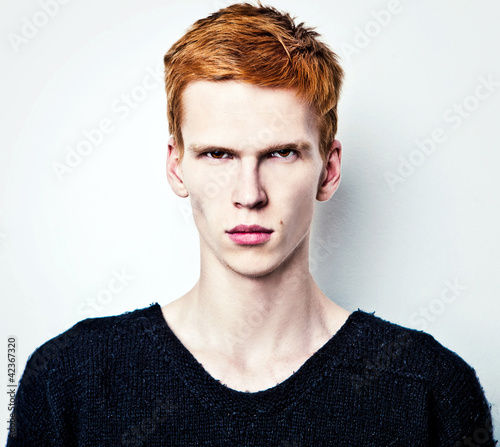 Naklejka ścienna Young red haired man on light background.