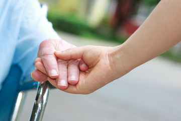 Wall Mural - Senior women in wheelchair holding hands