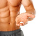 © Dash - Close up of muscular man torso with hand full of pills