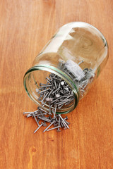 Wall Mural - Metal nails and glass jar on wooden background