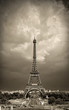 Vintage styled image of Eiffel tower during daytime, sepia toned against the dramatic sky. Paris, France