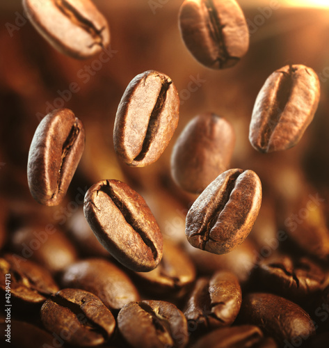 Fototapeta na wymiar Fragrant fried coffe beans with focus on one are falling