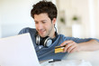 © goodluz - Young man buying music on internet with tablet