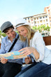 © goodluz - Young couple sitting on public bench to read touristic map