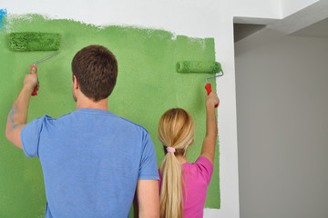 happy couple paint wall at new home